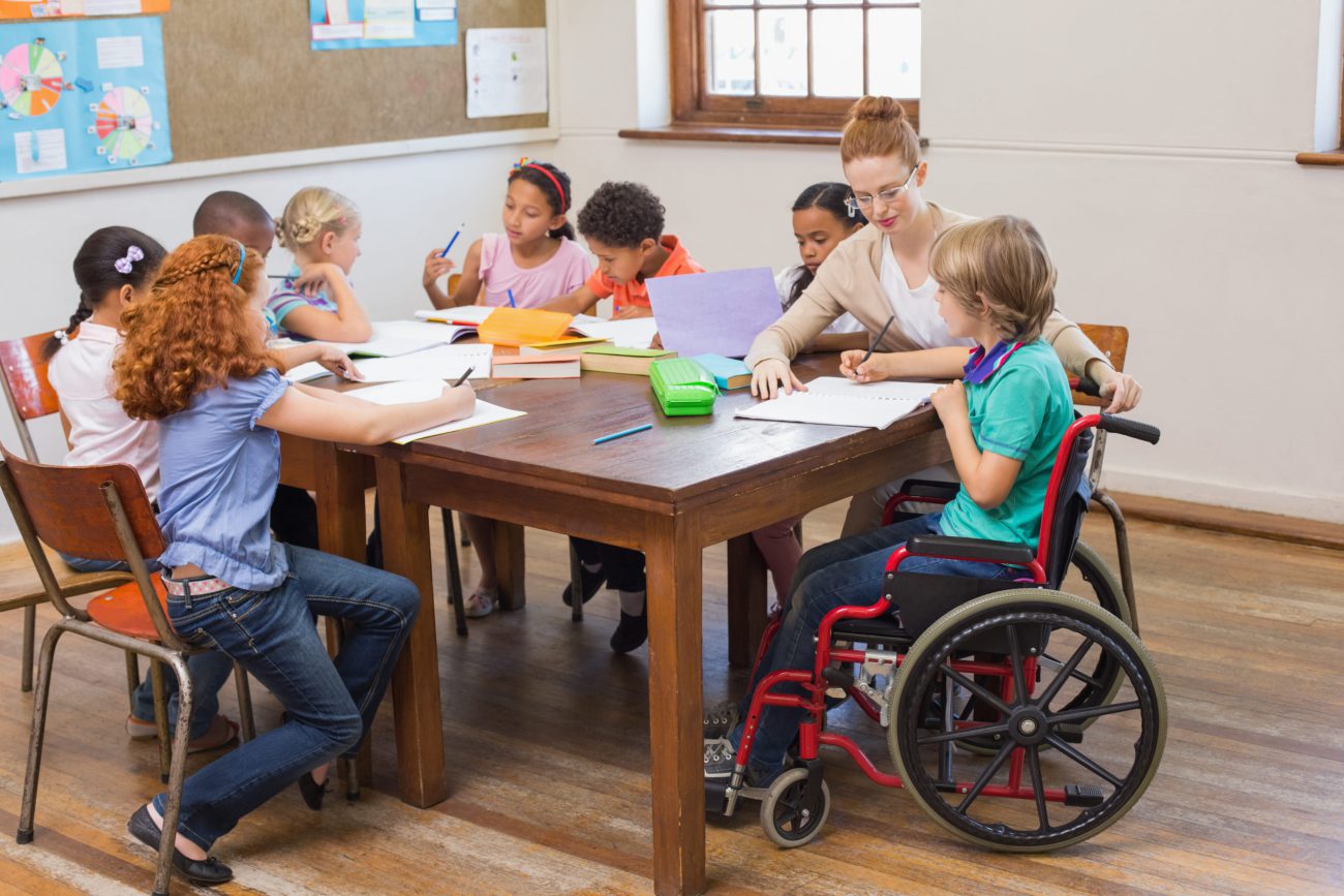 Pretty teacher helping pupils in classroom at the elementary school